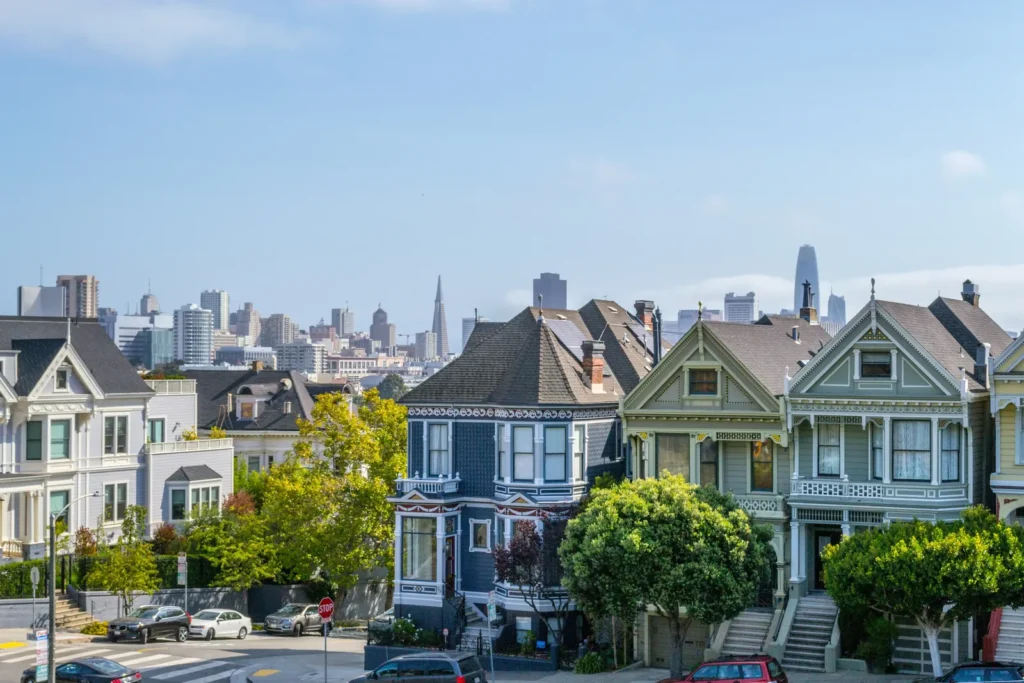 Row of California Victorian homes with the San Francisco city skyline in the background