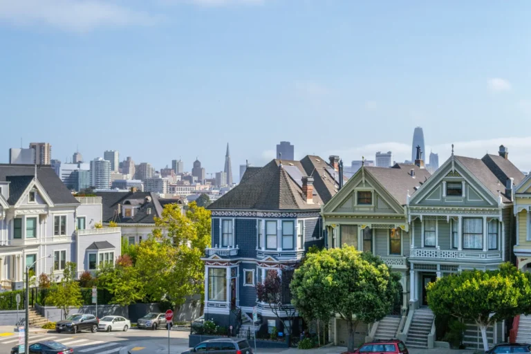 Row of California Victorian homes with the San Francisco city skyline in the background